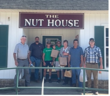 A group stands in front of a store named The Nut House.