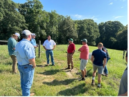 A group of men talk in a pasture.